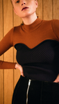 The Kaare Top in Black/Brown. With a seamless mock neckline, heart shape bustier layered in lightweight knit top. Designed to be slim fitting. Pulls on.