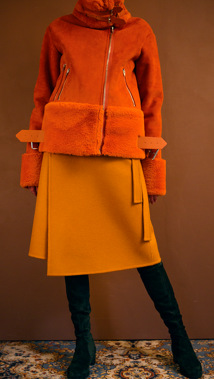 Moto-style suede shearling jacket fully lined in orange shearling. Super soft in suede, dropped shoulder, extra long sleeves with soft shearling detail at cuffs, front zip pockets, gusseted back panel, belt at waist with bucket closure, zip closure with attached wide belt in belt loops, Medium-weight. Fully lined. Oversized. Relaxed silhouette.