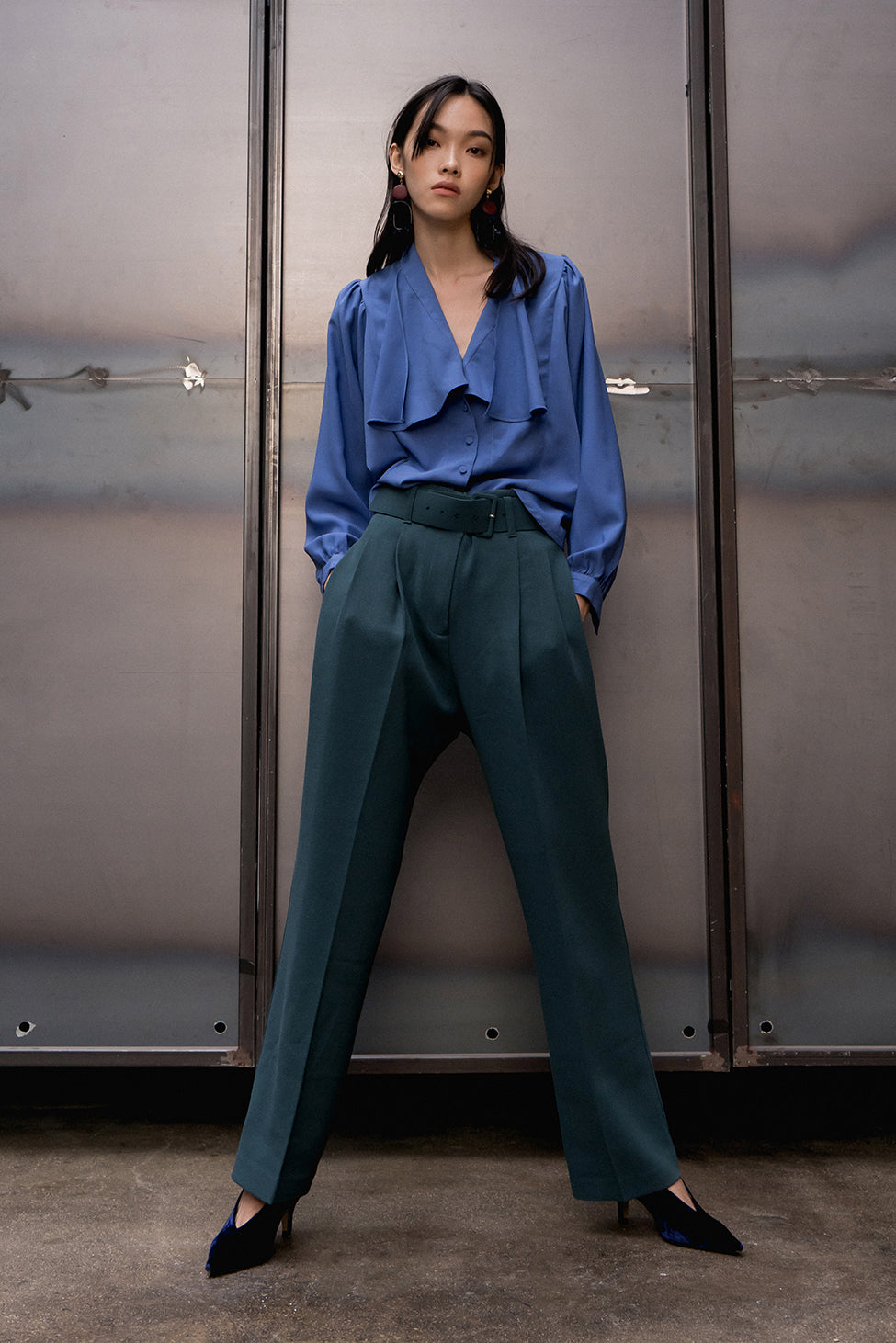 The Lizzie Top featuring wide V-neckline, long sleeve with button cuffs, asymmetrical ruffle detailing. Full-button placket. Slightly cropped length. High-low.