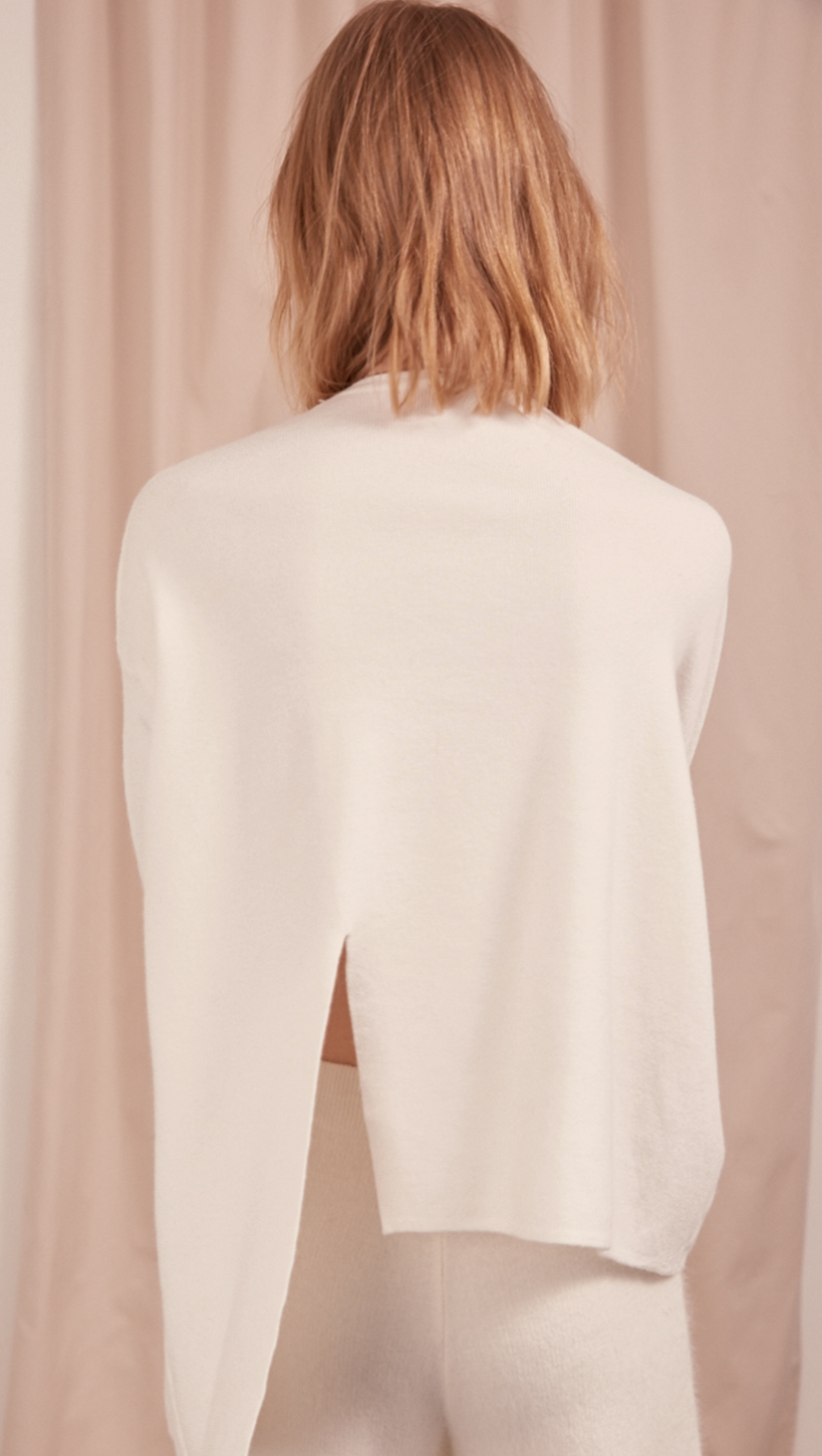 The Arie Sweater in off-white. Features round neck with cut out panel, asymmetric hem, back slit, sliver-tone hardware ring with hook closure. Pull on. Slightly relaxed fit.