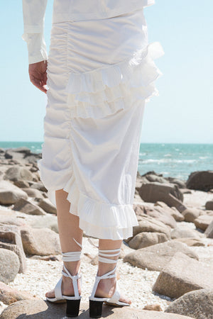 The Aurélie Skirt in White featuring layered ruffles and cut on a bias. Asymmetrical hem. Concelaed side zip closure. Layered ruffles. Partial lined. High rise. 