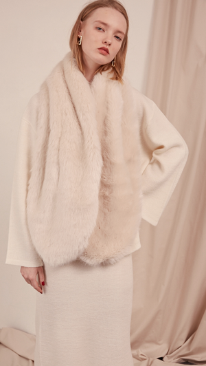 The Beaumont Scarf in faux fur. It features a cream ivory with a neat slip-through fastening and also can be layer it over the lapels of outerwear. 