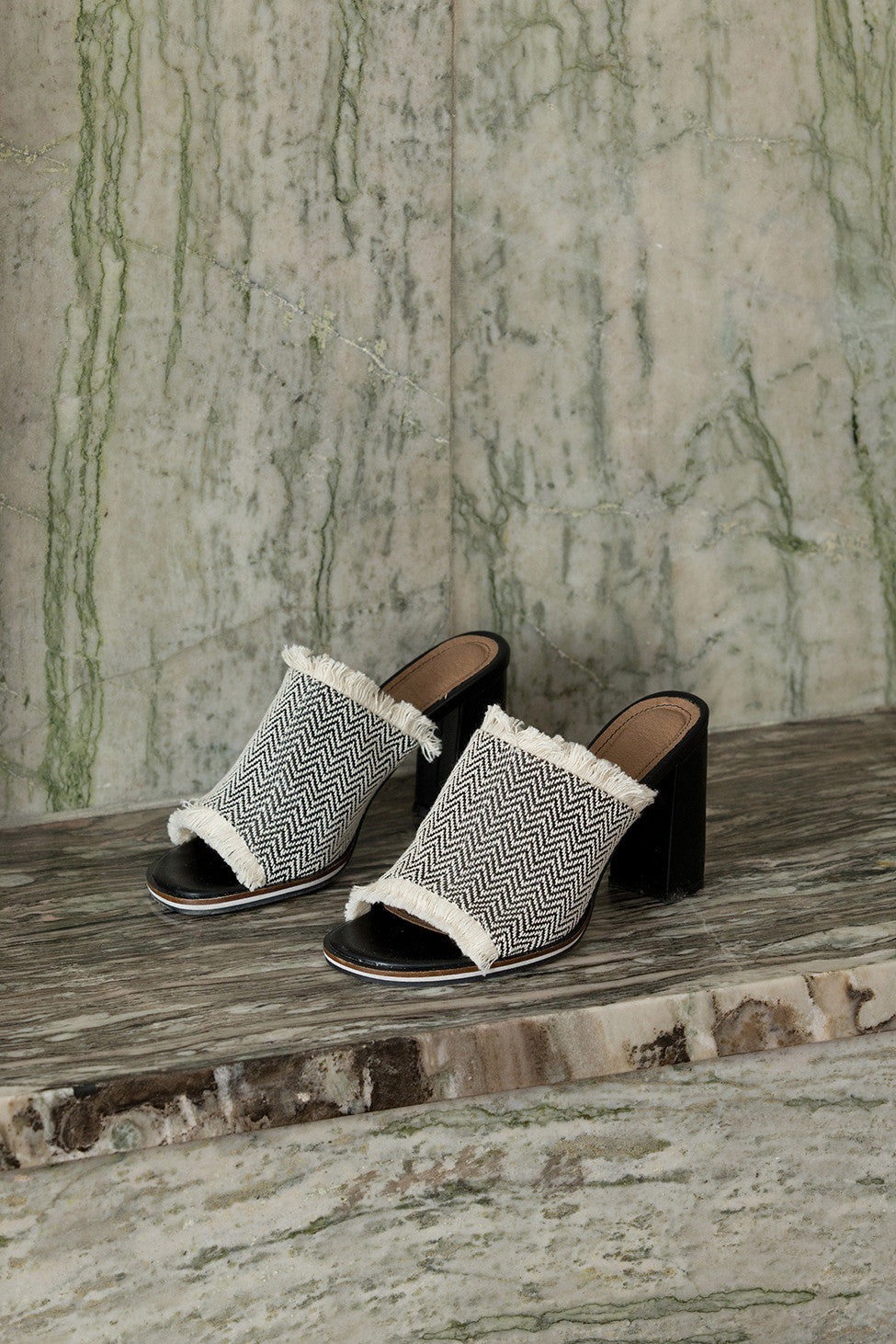 The Brioni sandal in Black-and-White chevron pattern. Open toe. Wool carpet fiber upper with tassel detailing. Slip-on design.