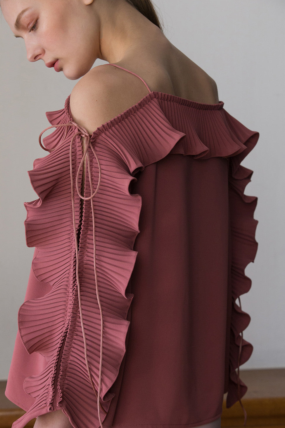 The Calin Top in Pink, featuring thin straps, square neckline, dimple sleeves in ruffle detailing with self-tie. Pull on.