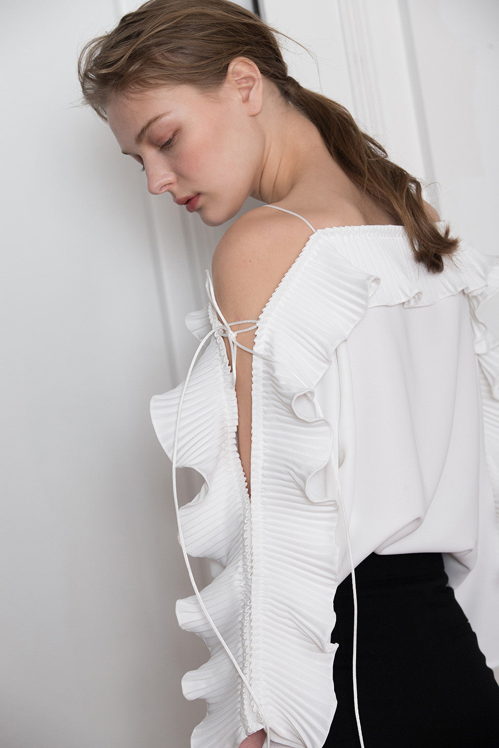 The Calin Top in White featuring thin straps, square neckline, dimple sleeves in ruffle detailing with self-tie. Pull on.