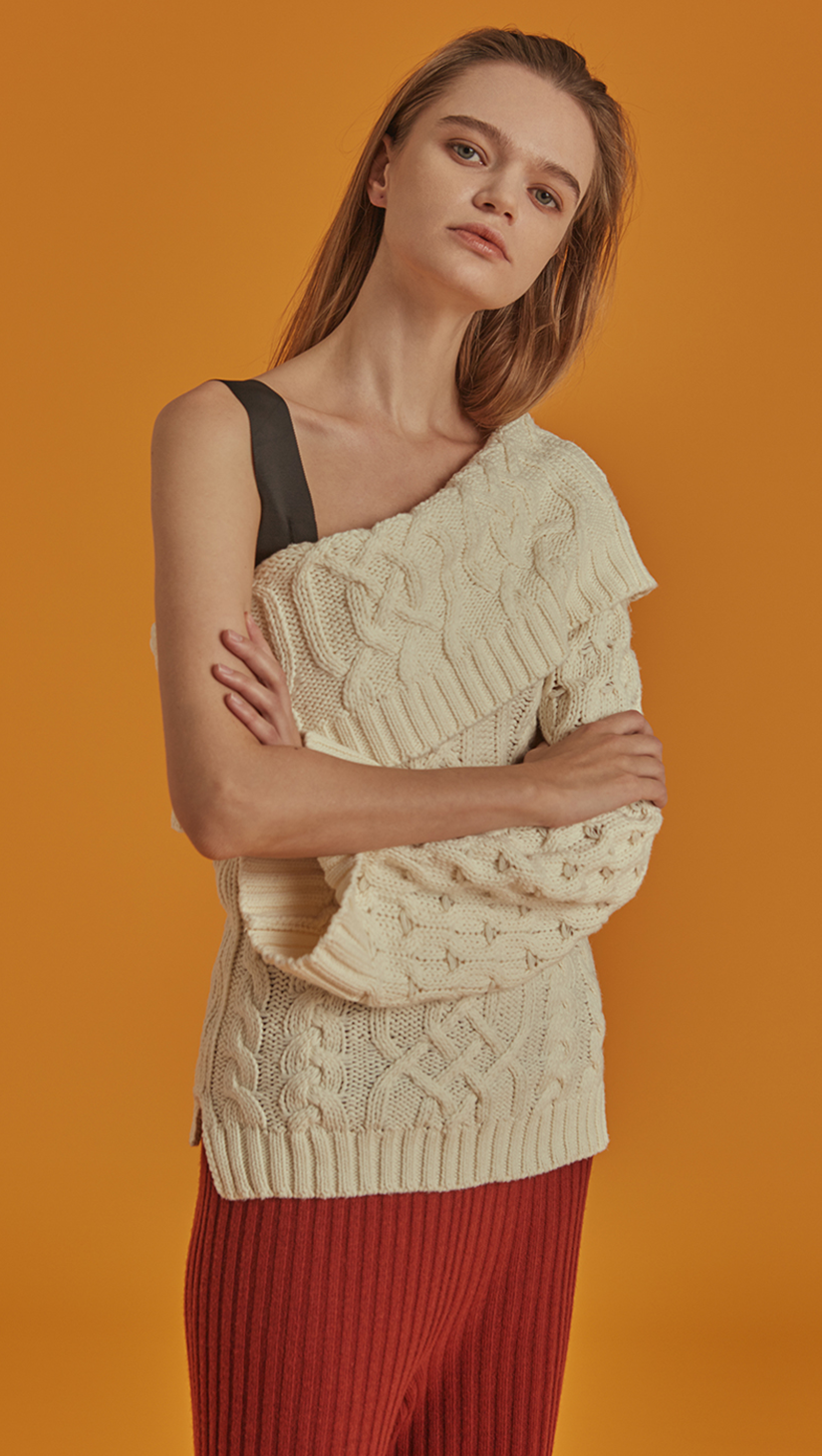 Celina is a cable knit in Ivory with a flattering one-shoulder silhouette. Drop shoulder design, long sleeve, detachable shoulder strap in button closure. Pull on. Straight fit. 