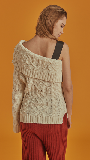Celina is a cable knit in Ivory with a flattering one-shoulder silhouette. Drop shoulder design, long sleeve, detachable shoulder strap in button closure. Pull on. Straight fit. 