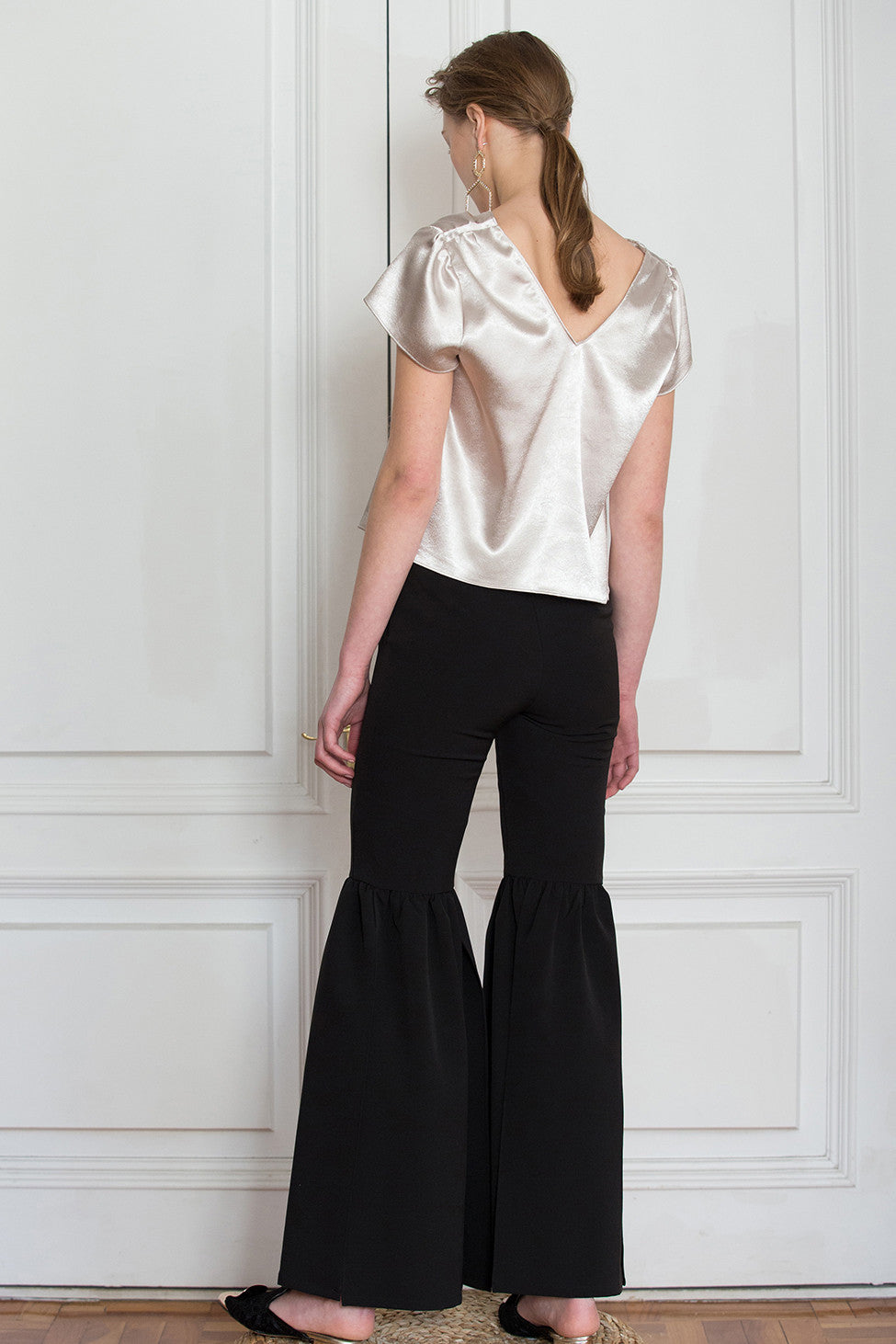 The Cheysa Pant in Black featuring peplum leg trouser, gently flare out hem with side slits. Slim-fitting at thigh. High rise. Centre-front concealed zip fly and hook closure.