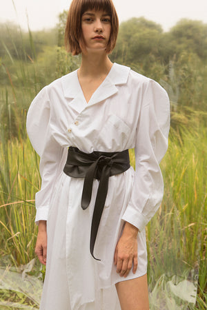 Shirt dress in White. V-neckline with pointed collar with button placket. Dropped shoulders. Long sleeves with balloon puffs. Adjustable and removable leather belt tie. Shirttail hem. Straight silhouette in asymmetric length. Ankle length.