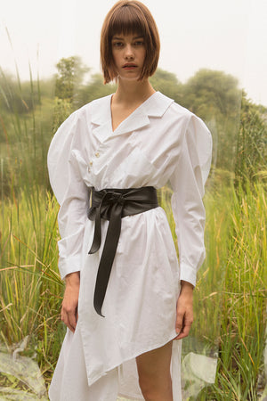 Shirt dress in White. V-neckline with pointed collar with button placket. Dropped shoulders. Long sleeves with balloon puffs. Adjustable and removable leather belt tie. Shirttail hem. Straight silhouette in asymmetric length. Ankle length.