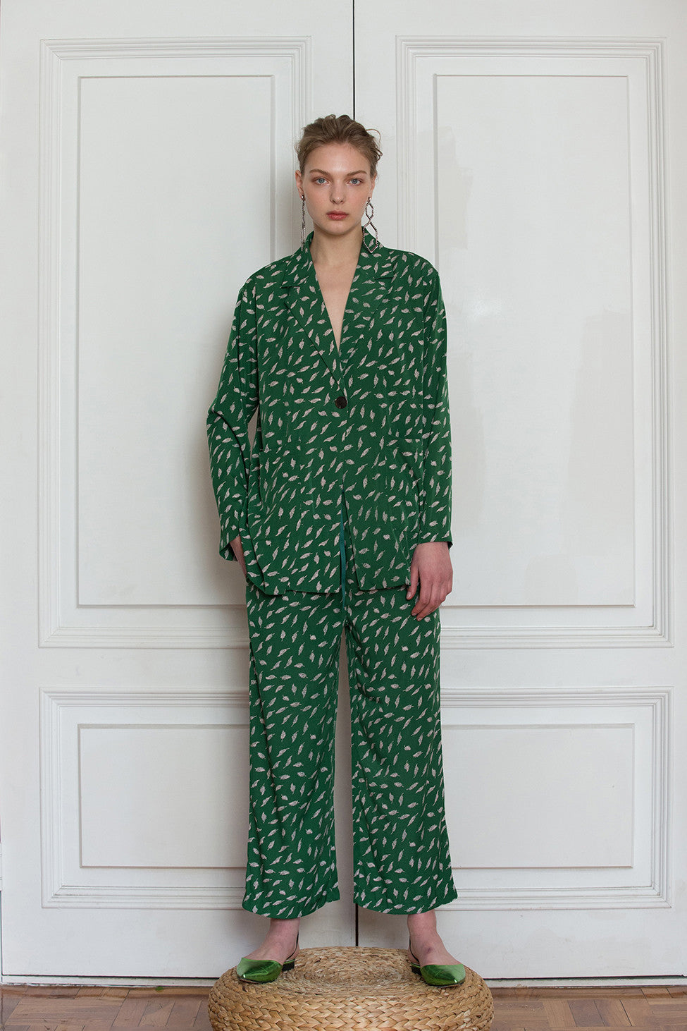 The Colette pajama set in Green feather-pattern. Top features notch collar with sharp lapel, long sleeves, one button placket, left chest pocket and straight hem. Pants feature a gathered elastic waistband and a straight leg. Relaxed fit.