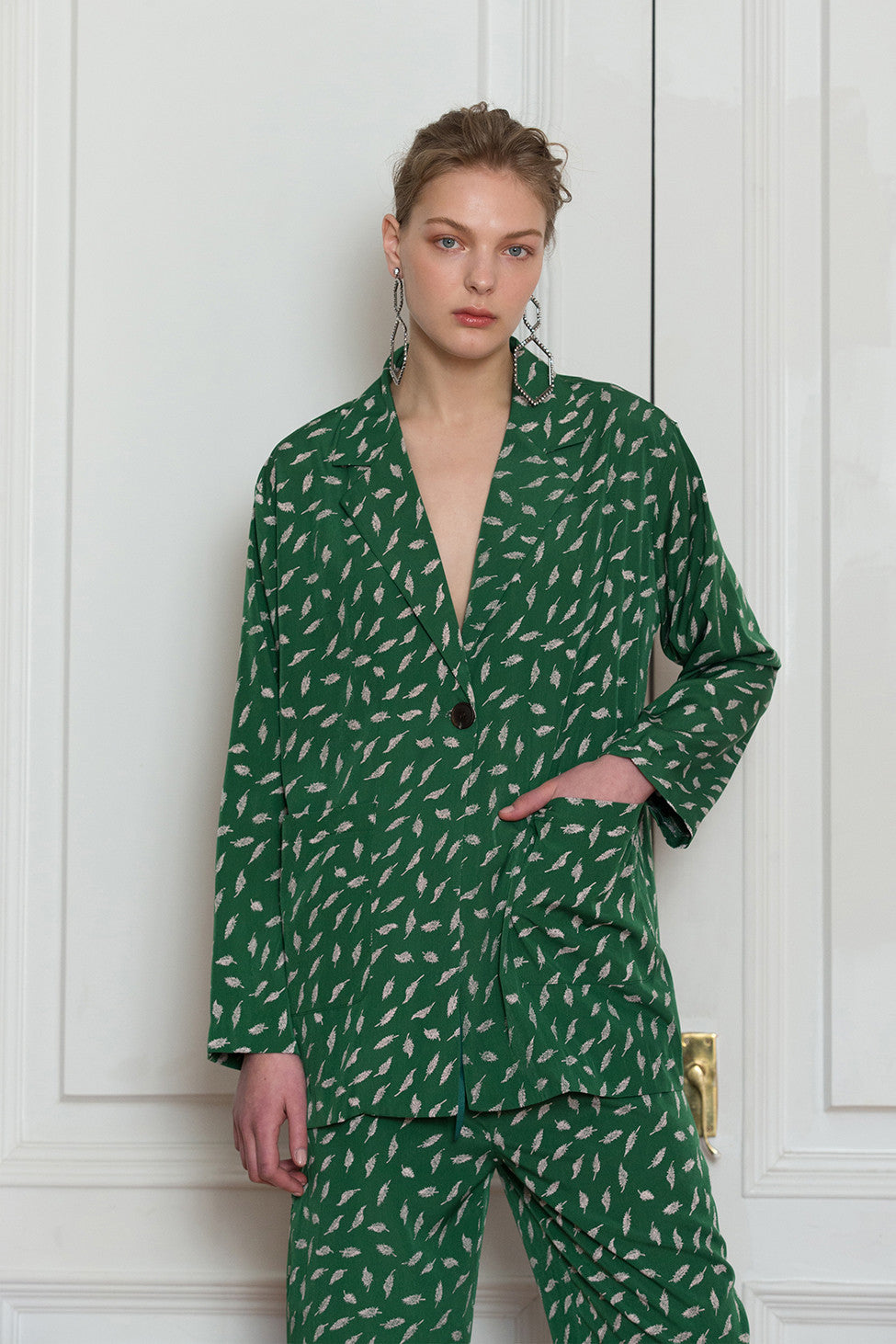 The Colette pajama set in Green feather-pattern. Top features notch collar with sharp lapel, long sleeves, one button placket, left chest pocket and straight hem. Pants feature a gathered elastic waistband and a straight leg. Relaxed fit.
