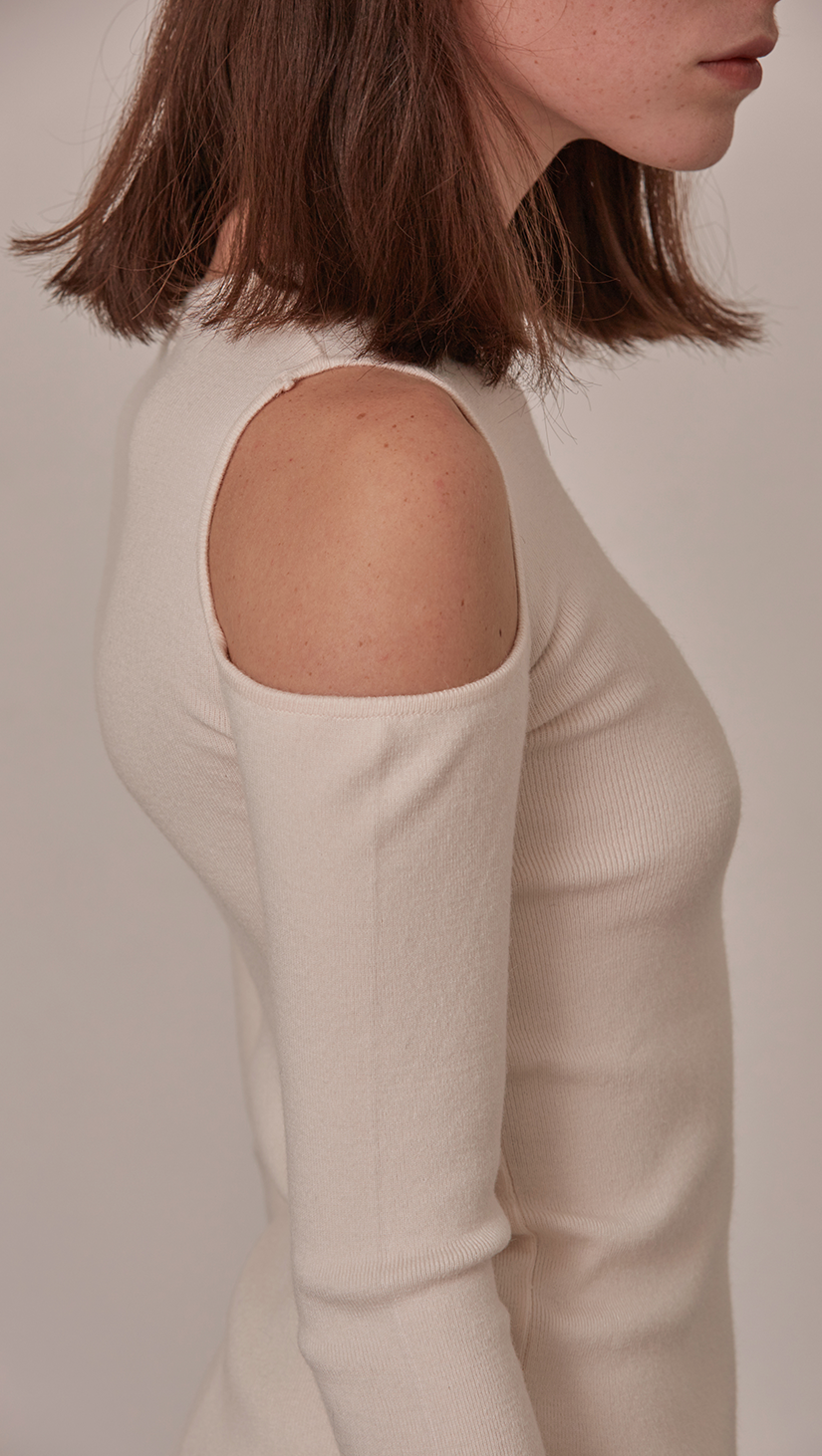 Daija Sweater in Ivory. The slim-cut with lightning slashes cutting through shoulder and creating a flattering buckle opening along side. Self-tied strap on sleeves. Super soft feel. Designed to skim the body.