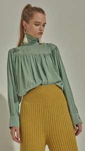 Faé Blouse in Mint. Soft-touch. High turtleneck collar with button closing, button closure at cuff. All-over raglan detailing. Designed to be loose fitting and relaxed. 