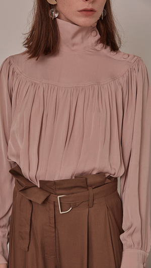 Faé Blouse in Pink. Soft-touch. High turtleneck collar with button closing, button closure at cuff. All-over raglan detailing. Designed to be loose fitting and relaxed. 