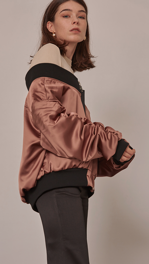 Farrow Off The Shoulder Bomber Jacket in Gold. Lustrous gold satin with oversized long ruched sleeves. Elastic off-the-shoulder banding. Front slit pockets. Zip fastening through front. Fully lined. Mid-weight. Designed to be loose fit. 