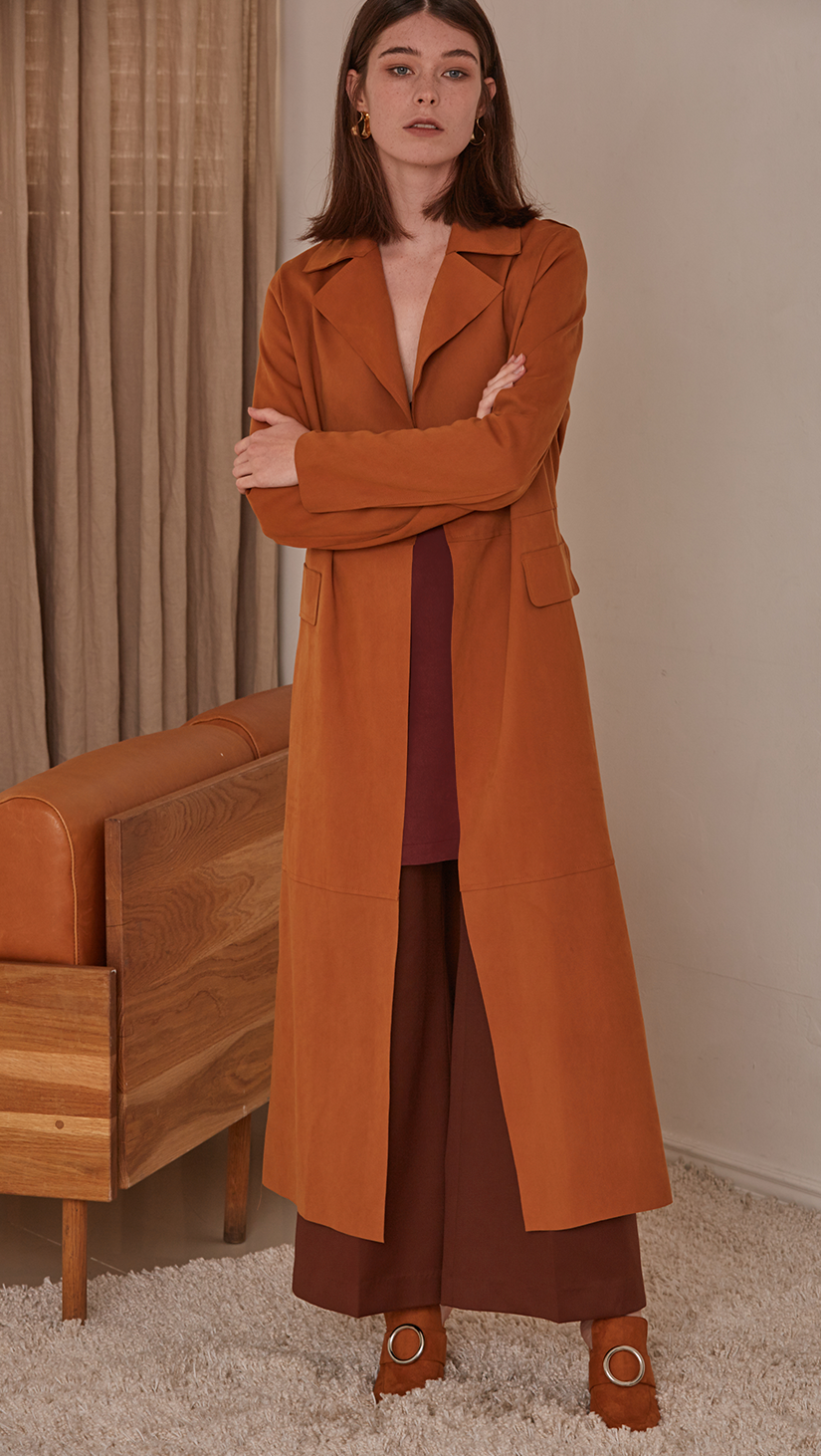 Vegan suede robe coat with tie in camel. No hardware, centre front tie closure. Pointed lapel collar and two oversize slip pockets at natural waist. Super soft suede feel. Straight hem. Designed to skim the body and have a dropped shoulder seam.