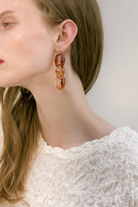 The Fiero, a pair of clear swirl acetate earrings in linked chain. Gold metal post back. Sold as a set.