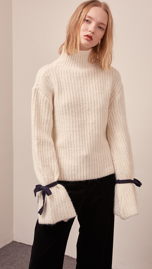 The Finn turtleneck sweater in off-white. Features long sleeve, wide bell cuffs with self-tie straps. Pull on. Relaxed fit.