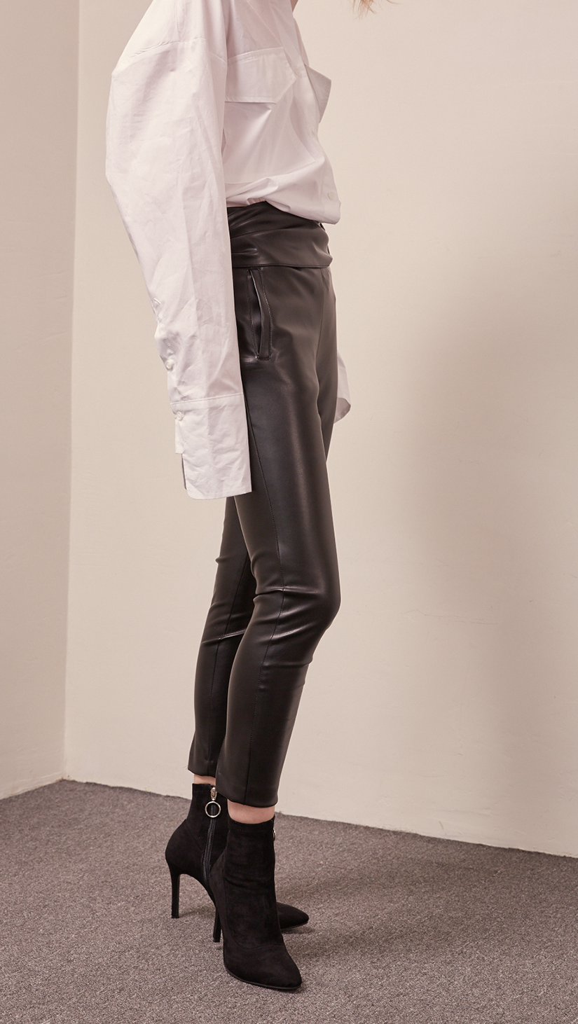 The Gwynn in black stretchy leather pant. Streamlining shape that ends above the ankles, buckled straps at the front, slant two pockets, zipper closing. Slim fit. Starchy Fabric. 