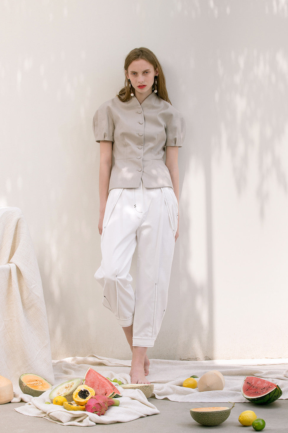 The Hanson Pant in off-white featuring pleats at front waist, slanted front pockets, tapered leg with rolled cuff with button closure. High-waist.