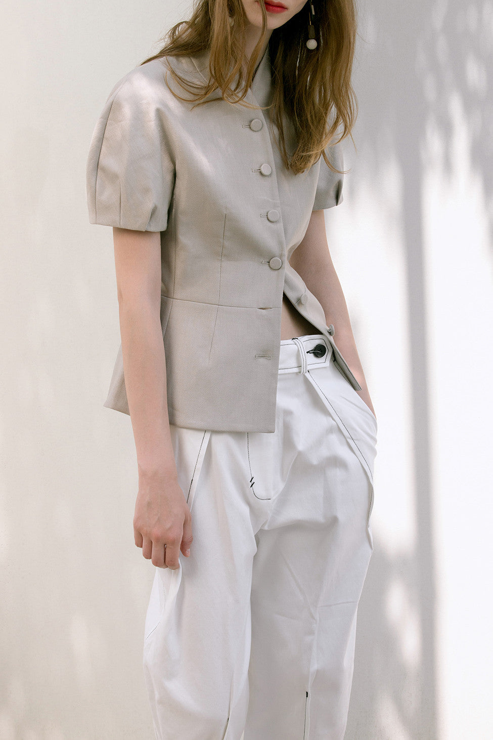 The Hanson Pant in off-white featuring pleats at front waist, slanted front pockets, tapered leg with rolled cuff with button closure. High-waist.