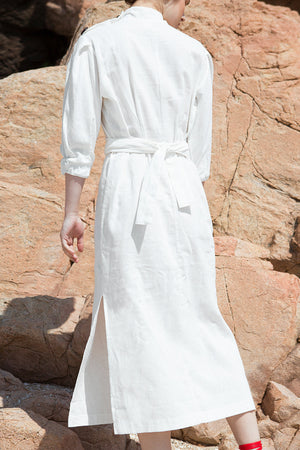 The Holland Dress featuring square neckline with oversized wood buttons, 3/4 sleeves with ruched cuffs, unmovable self tie belt, side slits. Pull on.