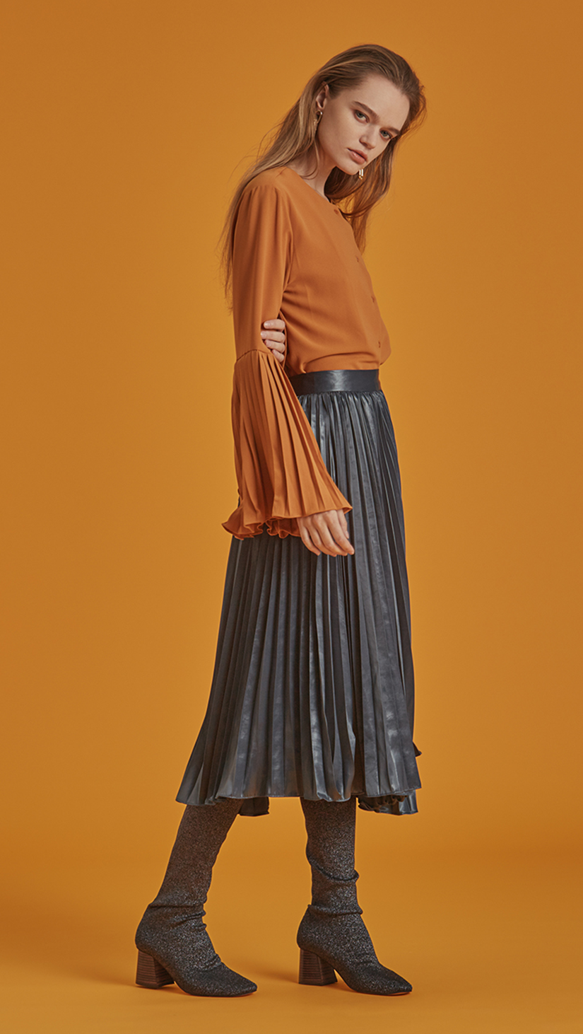 The Janye is a button-down blouse in non-sheer belled sleeves with accordion pleats. With a cowl neckline, slightly loose bodice and extra long sleeves.