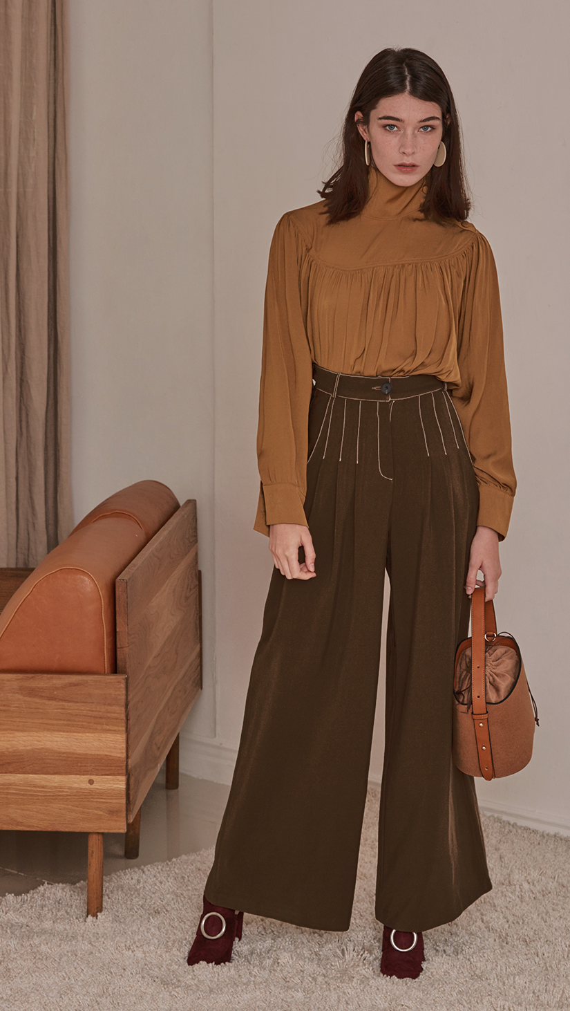 Kahn Pant, a stride wide in the darkest khaki shade. High waisted raglan pleated, deep waistband, zipper fly and tab closure. Fitted at the waist with leaving the fluidity of the trousers to flow.