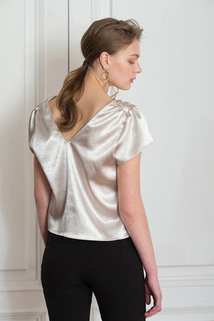 The Keena Top in Champagne featuring deep V-neckline, ruched short cap sleeves, button down closure. 