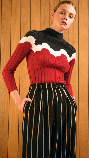 The Kismet Knit in red/black, a lightweight ribbed sweater. With a seamless mock neckline, raw edges. Pull on. Starchy fabric.