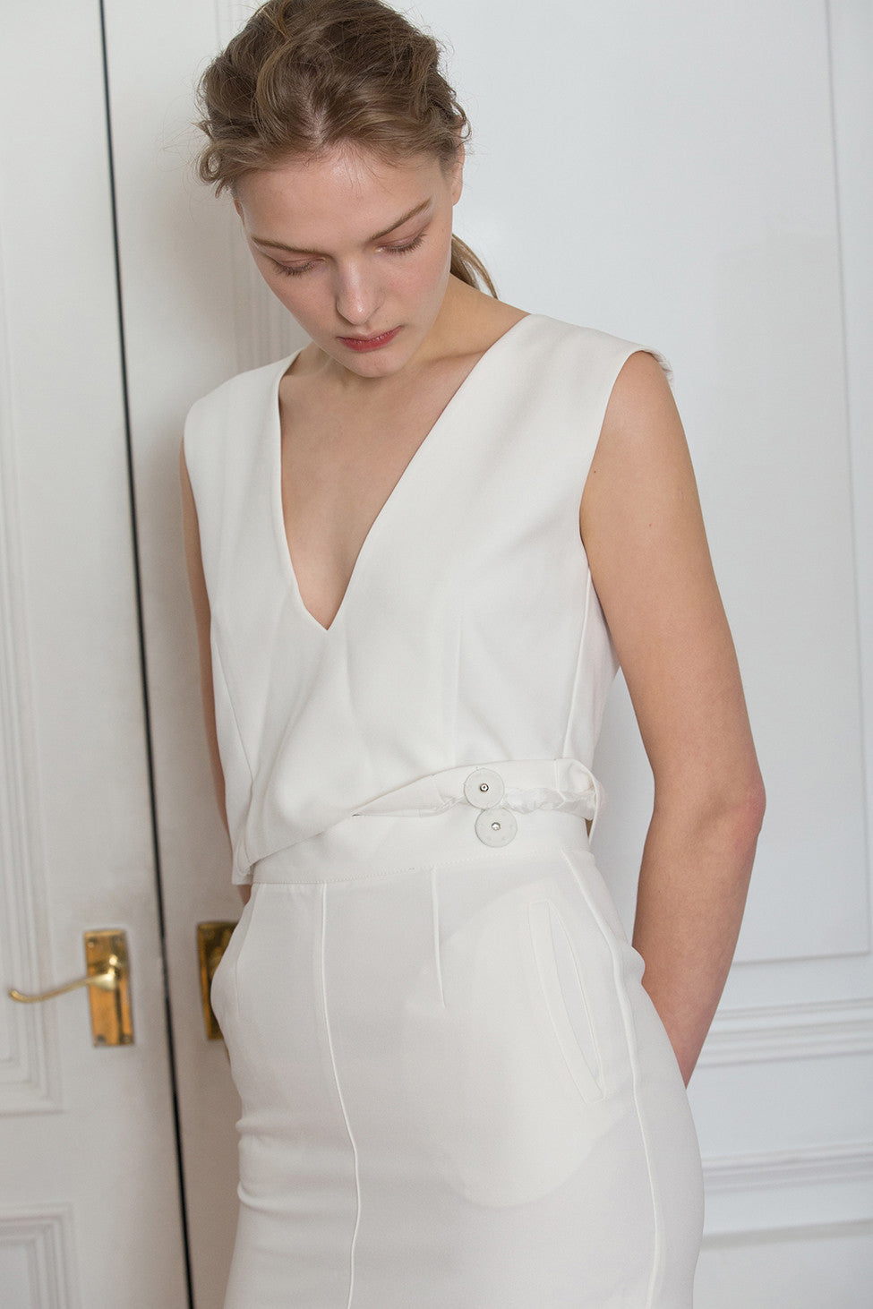 The Kole Dress in White, featuring deep V-neckline, sleeveless, open back in eyelet detailing with self-tie. Detachable snap button closure that can be worn separately as top and skirt. Skirt has a concealed zip fastening at the back.