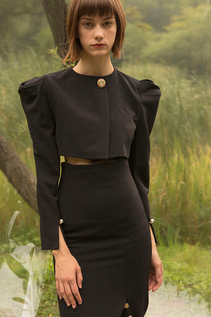 Padded shoulder with single button closure. Cropped length. Slits at cuffs. 