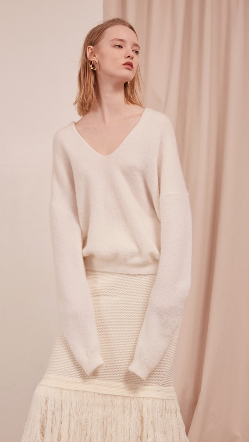 The Lilia Knit in off white. Features long sleeve, deep V-neckline, dropped shoulder. Pull on. Slightly loose fit.
