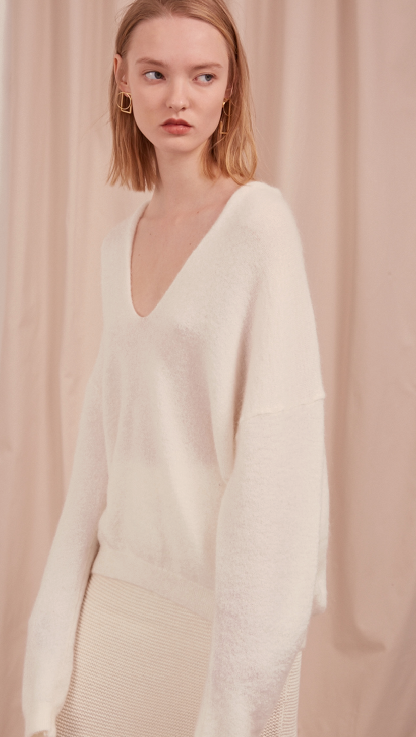 The Lilia Knit in off white. Features long sleeve, deep V-neckline, dropped shoulder. Pull on. Slightly loose fit.