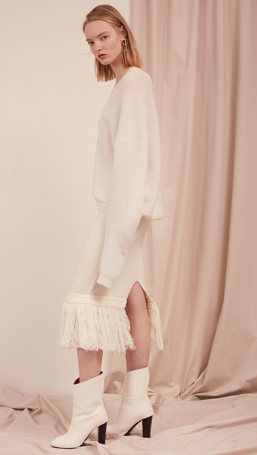 The Losara Skirt in ribbed knit off-white. With gathered elastic waistband, tassels hem, deep v back slits. 