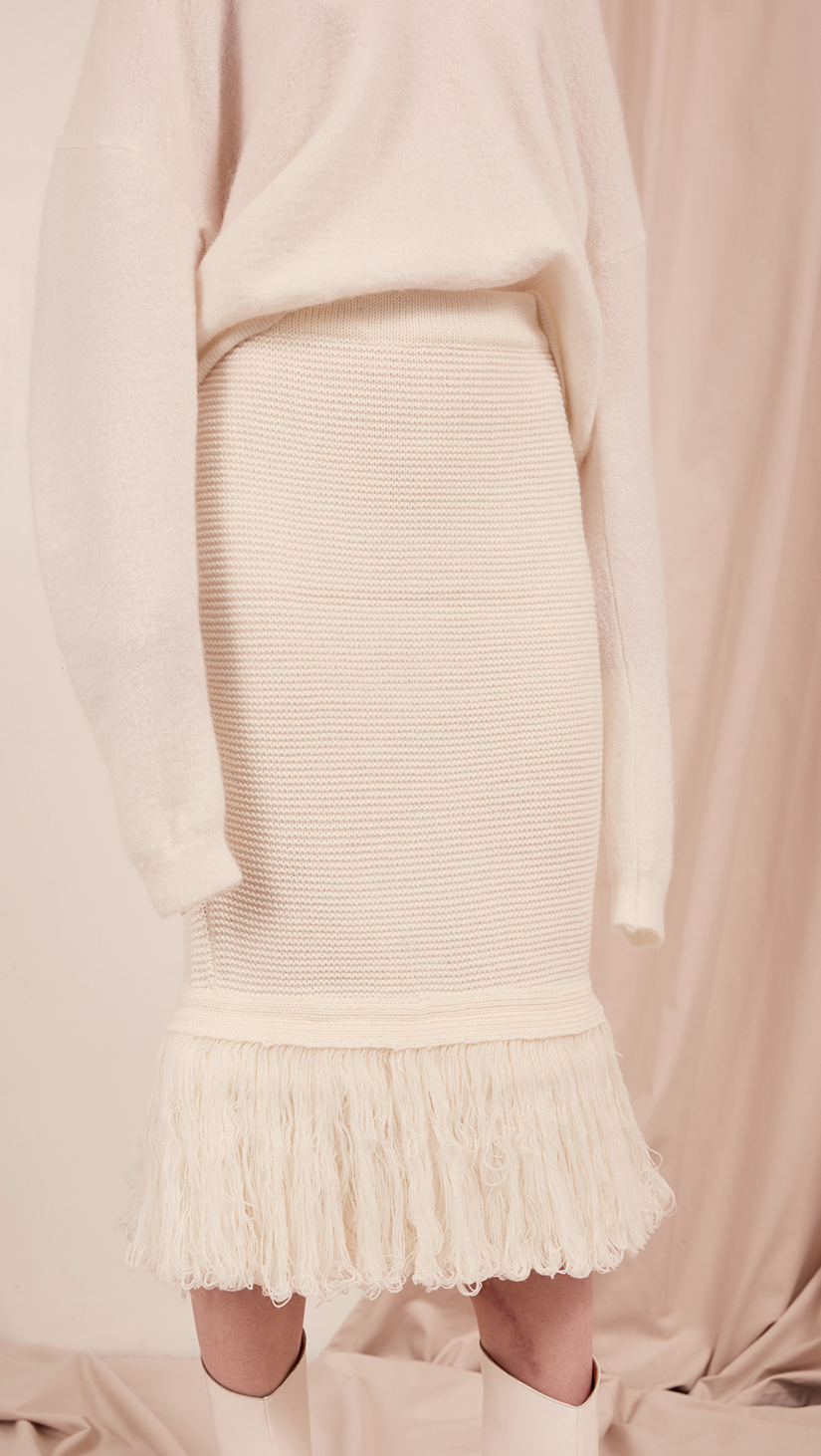 The Losara Skirt in ribbed knit off-white. With gathered elastic waistband, tassels hem, deep v back slits. 