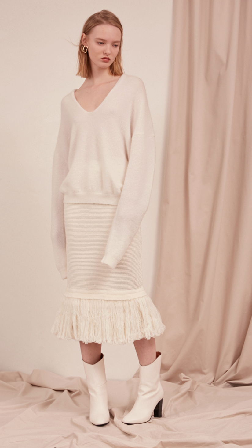 The Losara Skirt in ribbed knit off-white. With gathered elastic waistband, tassels hem, deep v back slits.