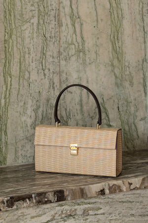 Malmo rattan bag in Beige. Top carry handle. Main compartment with front flap magnetic snap tab closure. Detachable shoulder straps.
