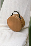 Marais bag in Brown. Woven round straw basket bag with fabric insert. Top handles. Detachable shoulder straps. 