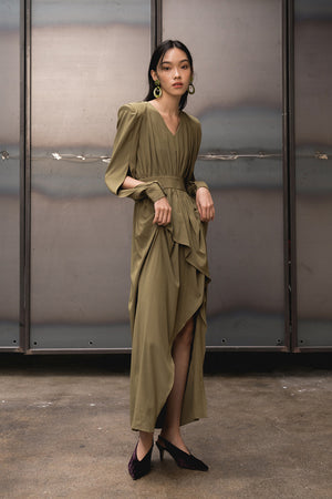 Deep V-neckline, padded shoulder, long sleeves with single button cuffs and deep slits. Concealed back zip closure. Floor length. Unlined. Asymmetric ruffle hem sewn on a bias. Gently flared silhouette.