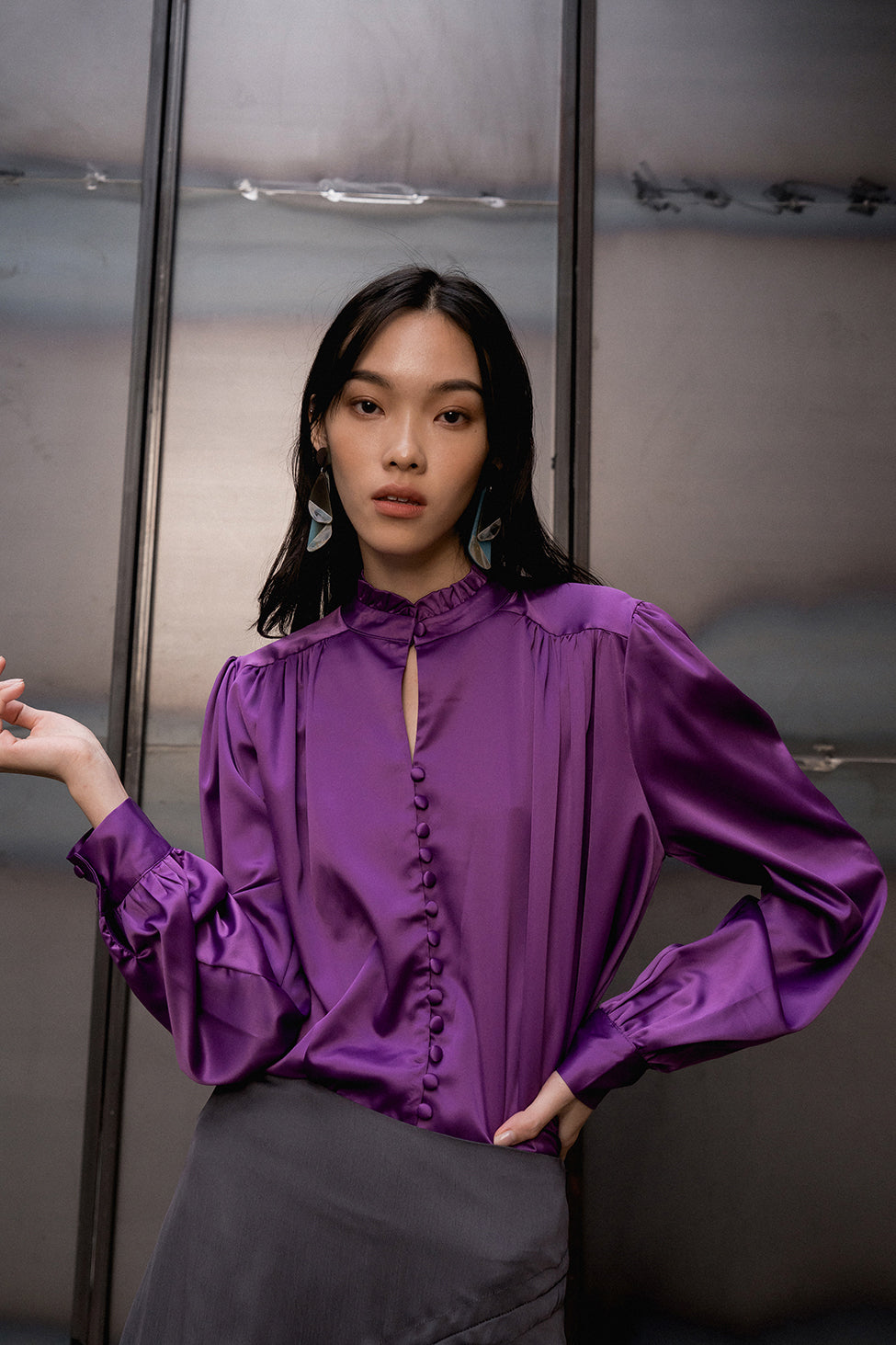 The Mariella silky top featuring band collar with ruched ruffles detailing, long sleeves with single-button cuff. Full-button placket. Relaxed fit.
