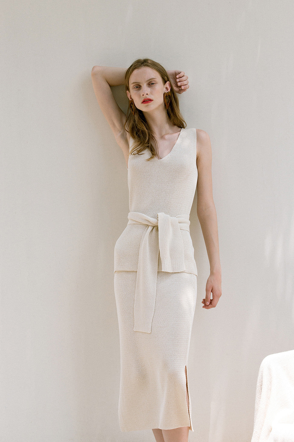 The Mikaela Top in lightweight knitted with V-neckline. Sleeveless. Detachable sash belt. Pull on.