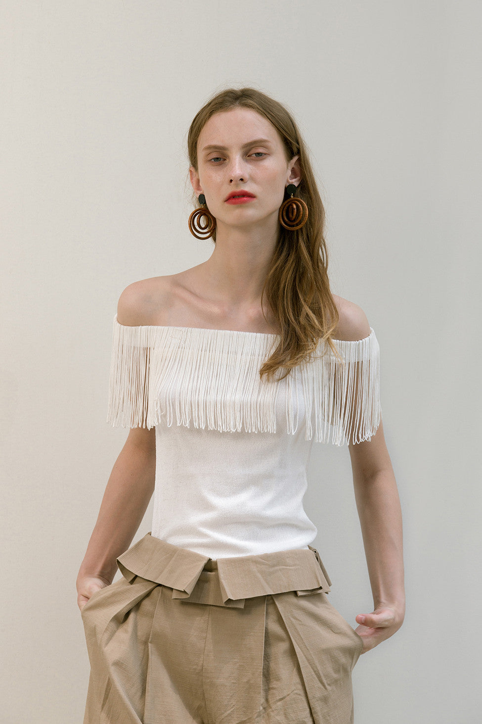 The Miquela Top in White featuring off-the-shoulder silhouette with tassel. Pull on. Slim fit.  