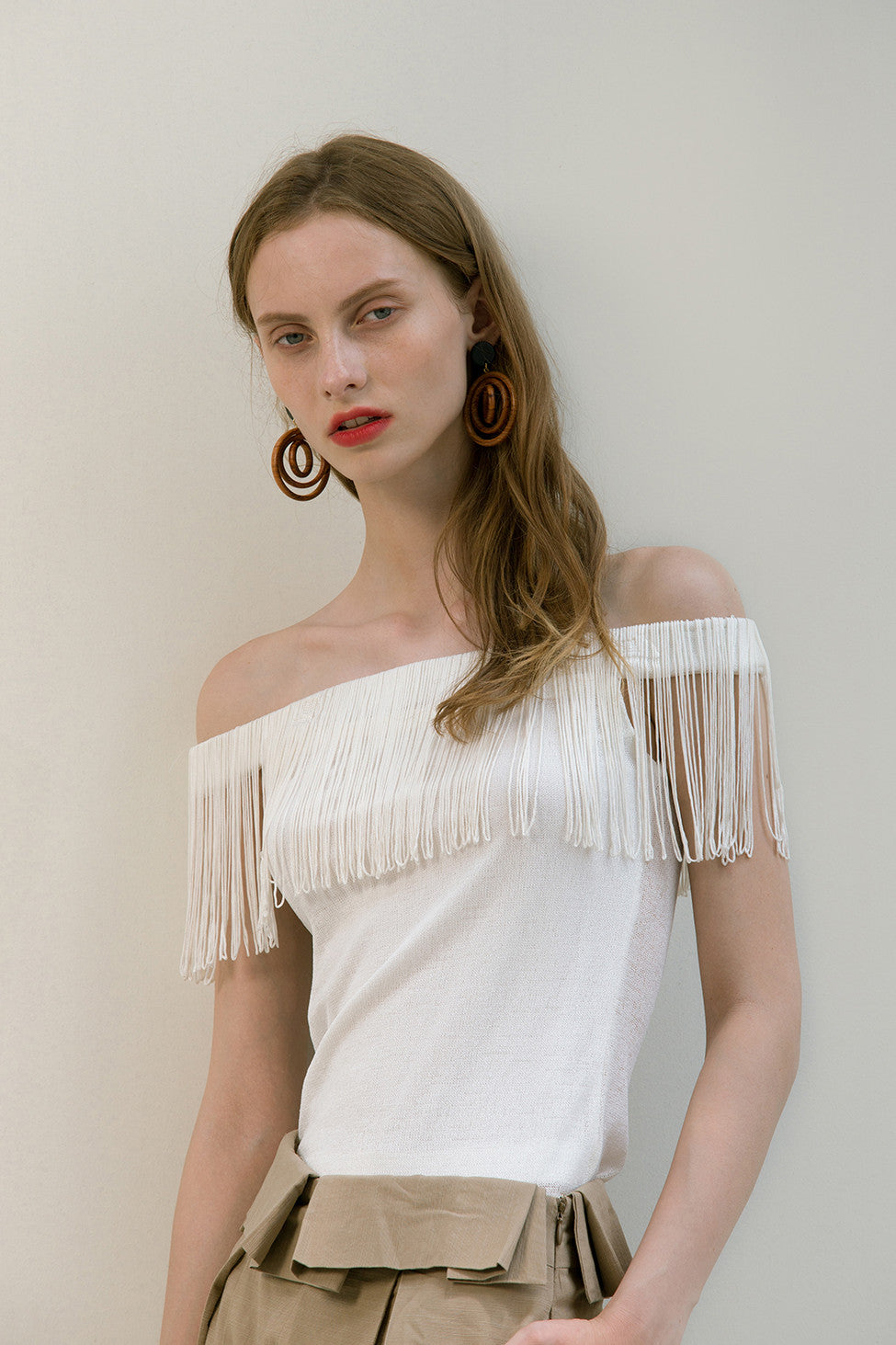 The Miquela Top in White featuring off-the-shoulder silhouette with tassel. Pull on. Slim fit.  