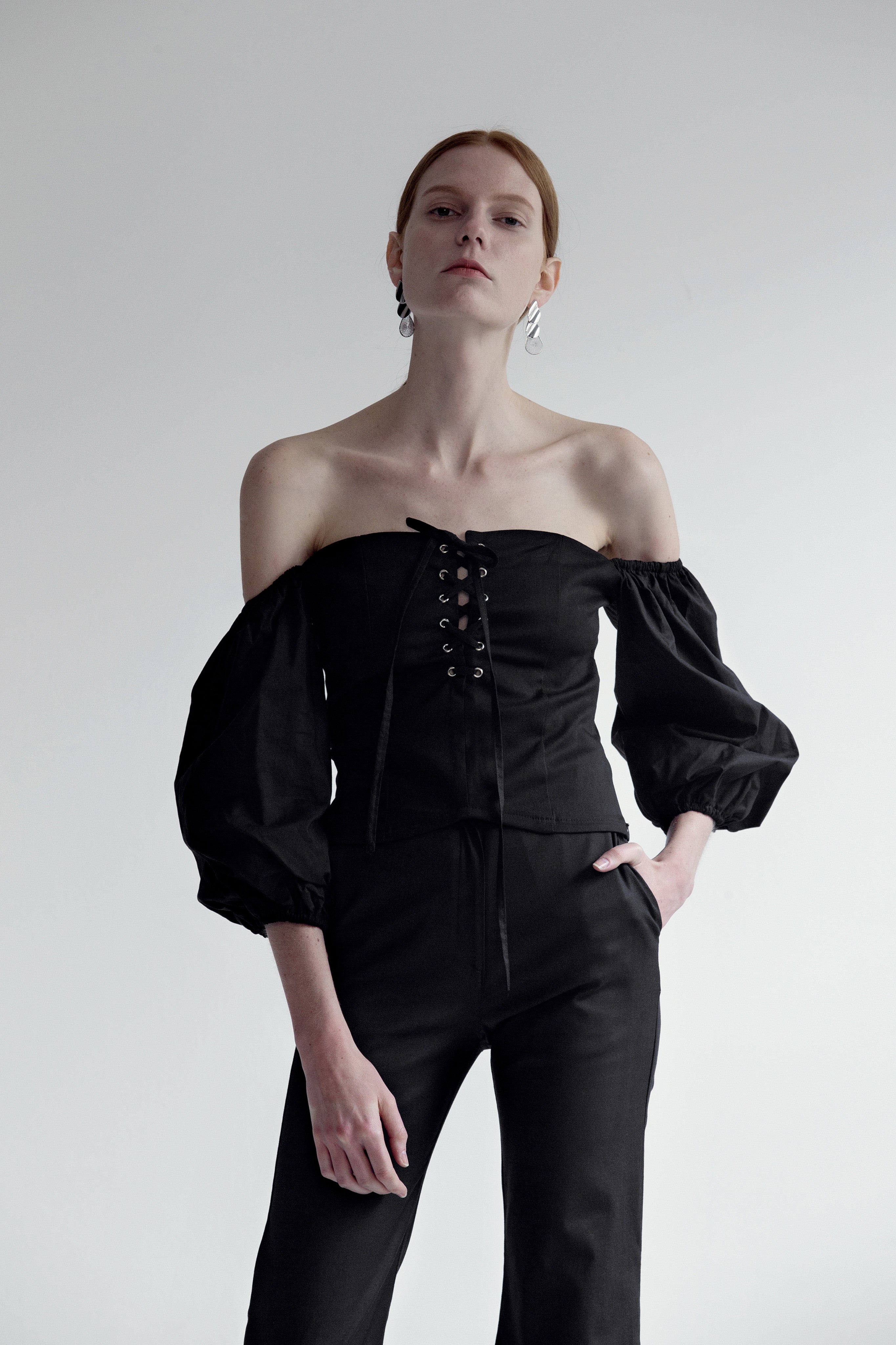 The Nahera Top in black featuring off-the-shoulder with long sleeves, self-tied closure and concealed zip opening along side. Cropped length.