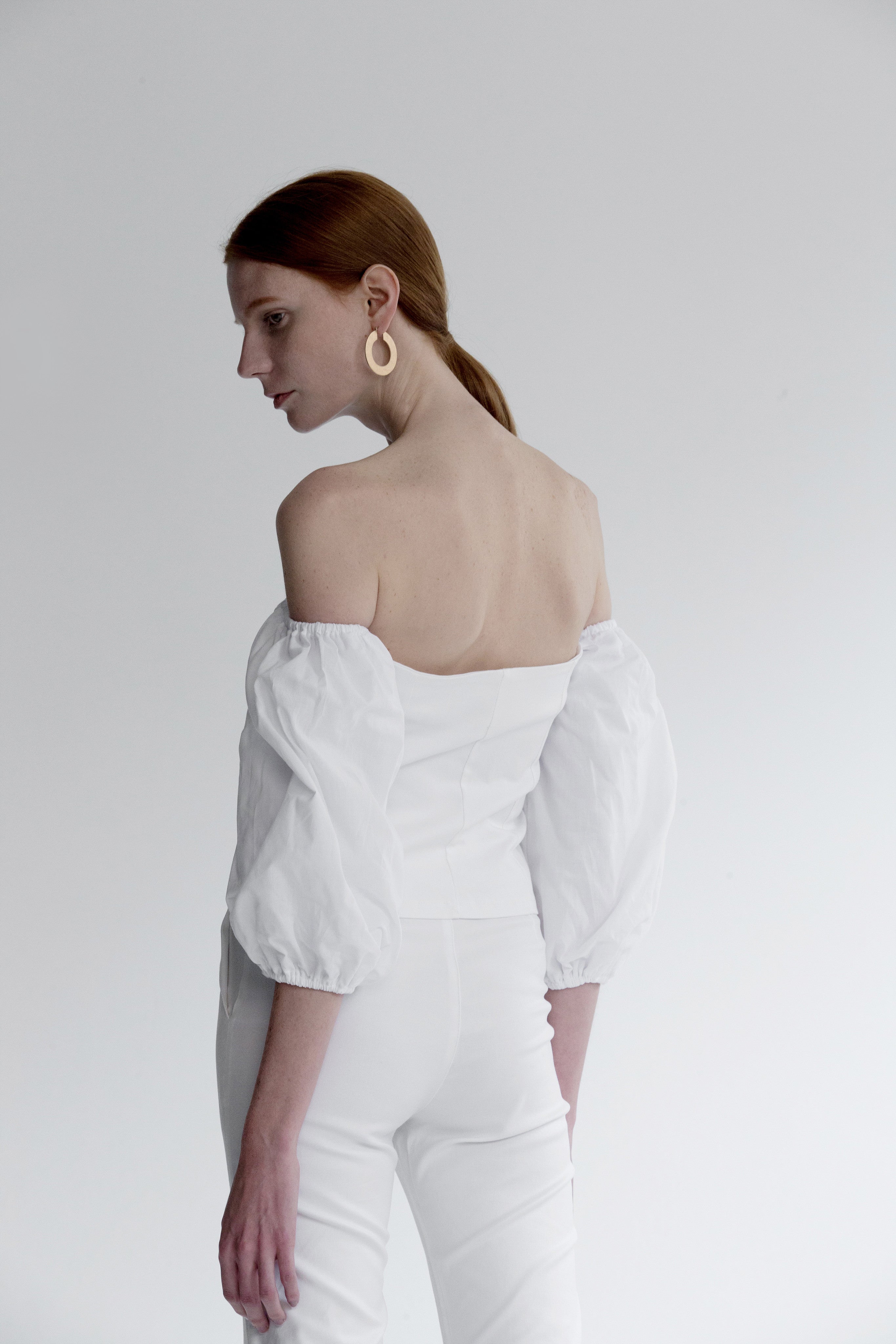 The Nahera Top in white featuring off-the-shoulder with long sleeves, self-tied closure and concealed zip opening along side. Cropped length.