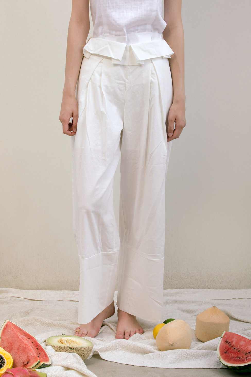 The Noelle Pant in white featuring pleated front with origami design, two slant pockets. Lightweight.