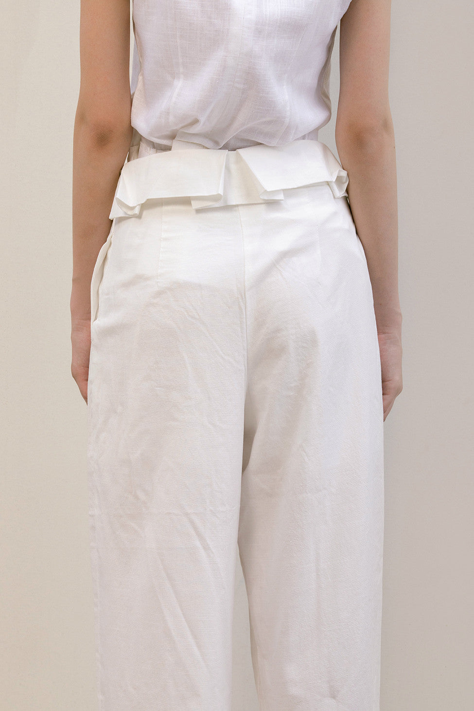 The Noelle Pant in white featuring pleated front with origami design, two slant pockets. Lightweight.