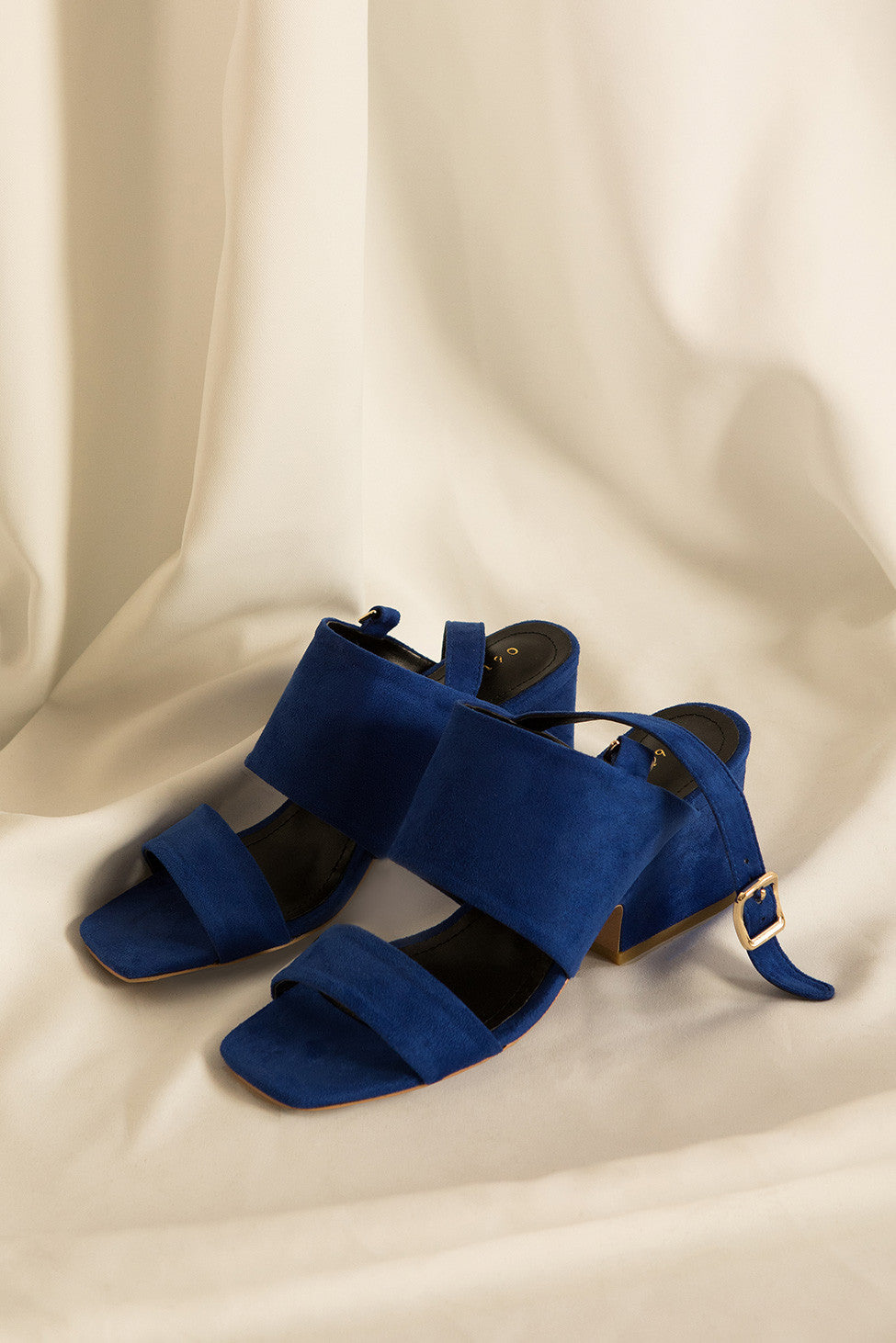 The Oleron featuring a straps across arch and around ankle with buckle, open toe. Covered block heel with rubber cap. Lightly padded footbed. 